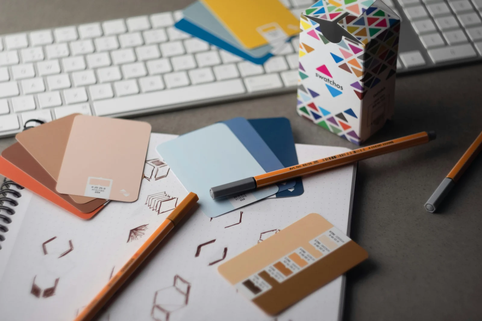 Brand colour swatches, logo sketches and printed collateral on a designer desk