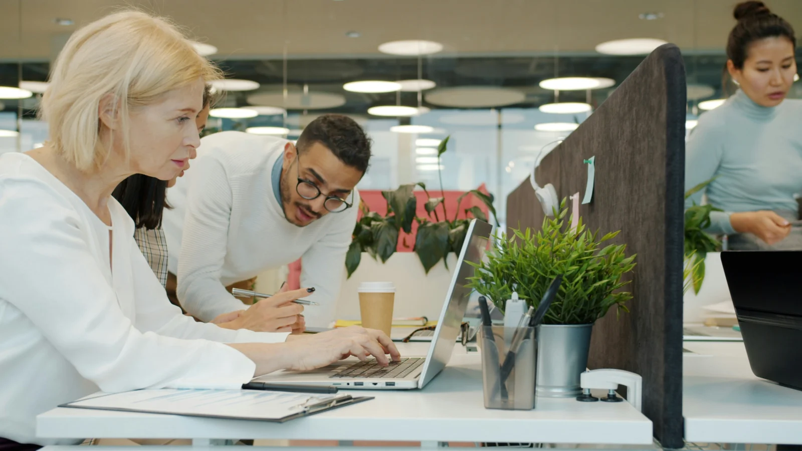 A mixed team of colleagues working together at computers in an office